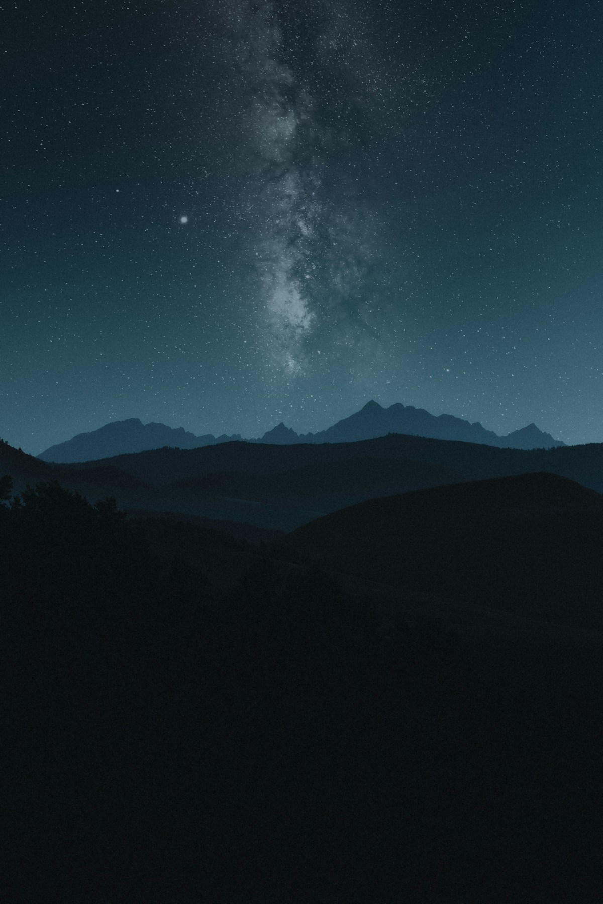 Milky Way arching over a mountain landscape photographed with a wide-angle lens at night