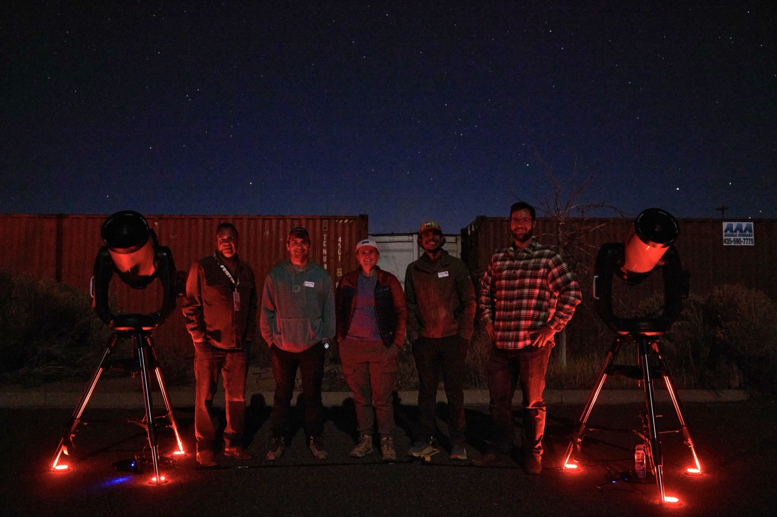 Happy tour group standing with two telescopes after a Bryce Canyon Stargazing night tour